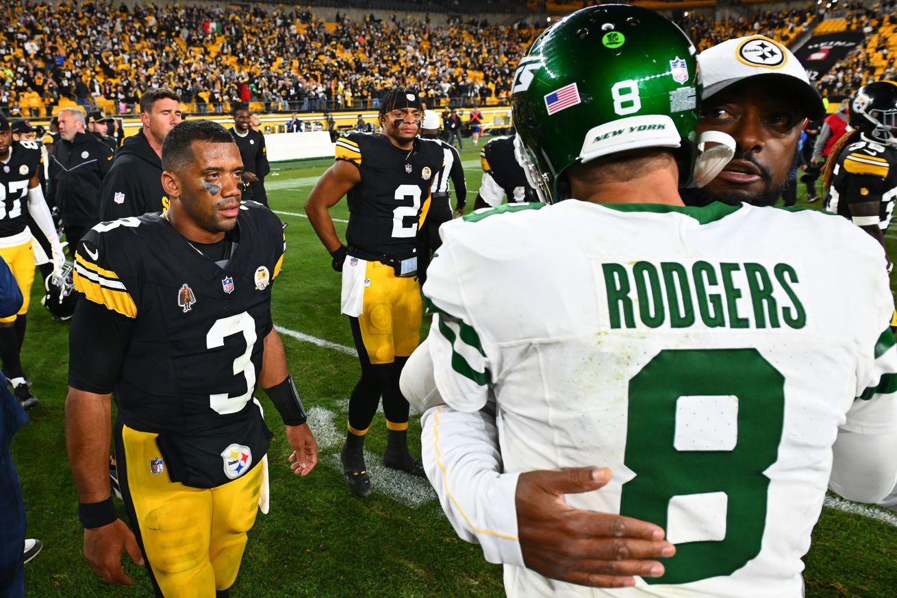 Russell Wilson #3 and Justin Fields #2 of the Pittsburgh Steelers look on as head coach Mike Tomlin of the Pittsburgh Steelers and Aaron Rodgers #8 of the New York Jets embrace after the game at Acrisure Stadium on October 20, 2024 in Pittsburgh, Pennsylvania.